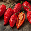 Red chili peppers on a wooden surface with one cut open to show seeds.